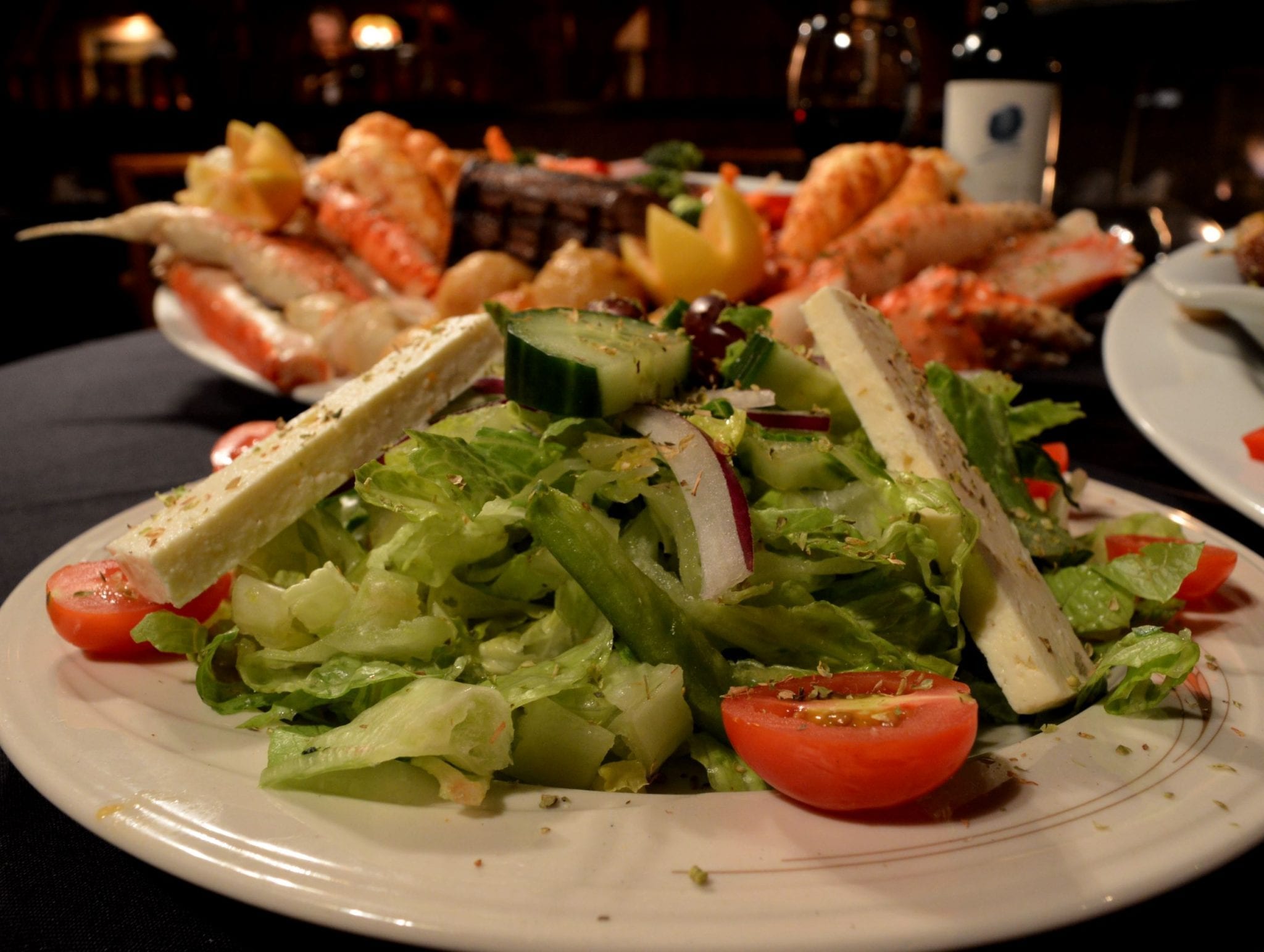 A salad in front of a surf and turf combo platter
